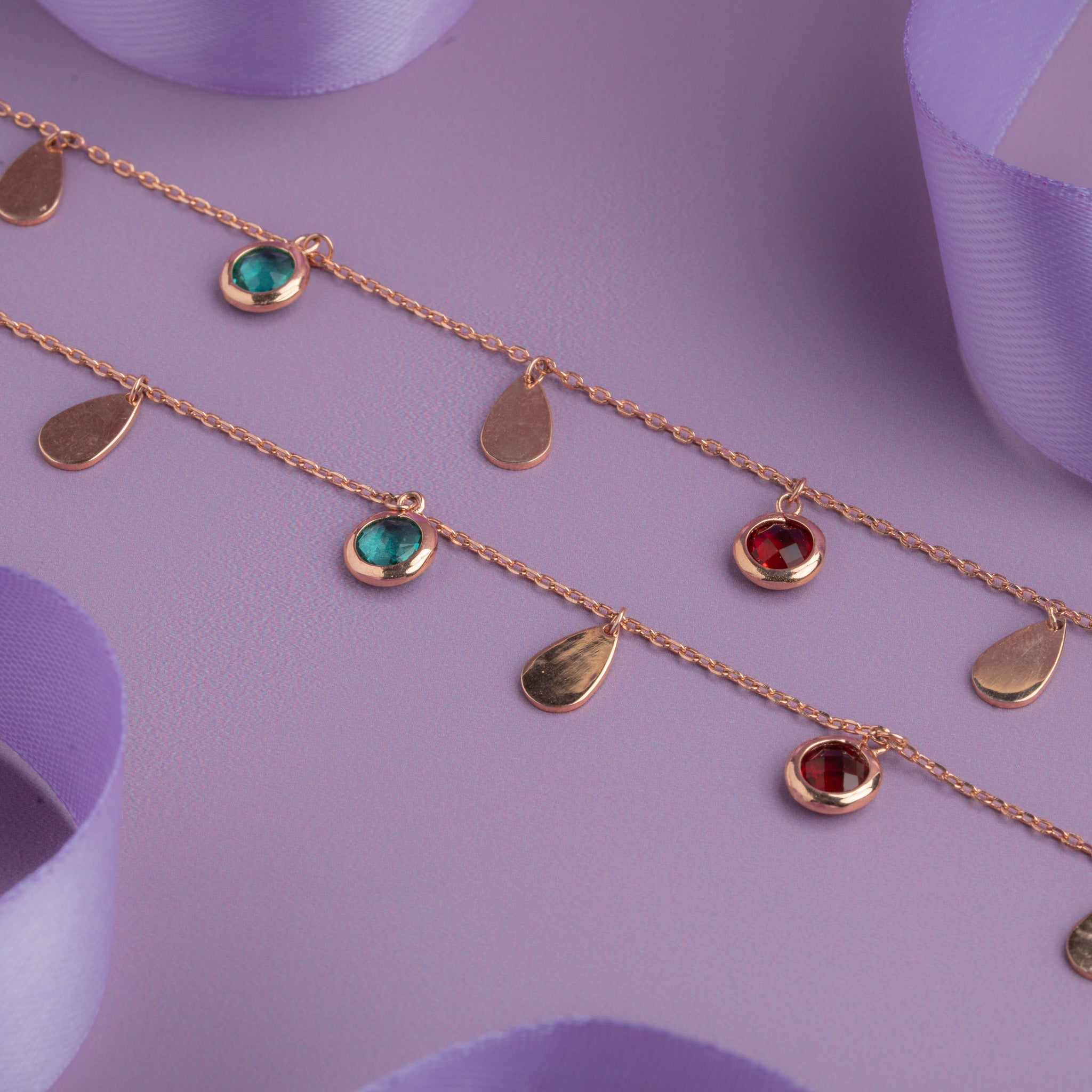 Rose gold anklet with teardrop charms and red and teal gemstone