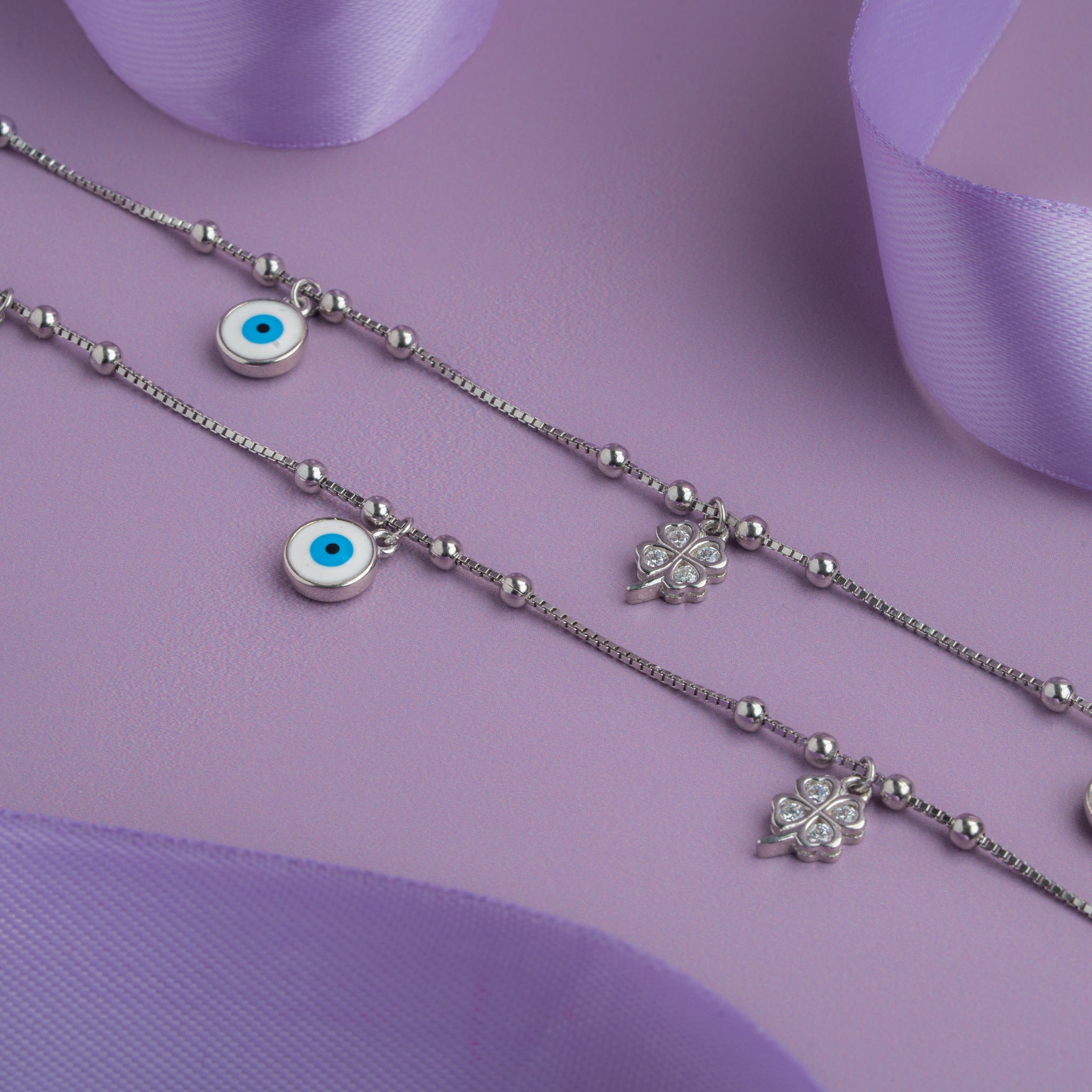 Silver anklet with evil eye and clover charms on a bead chain