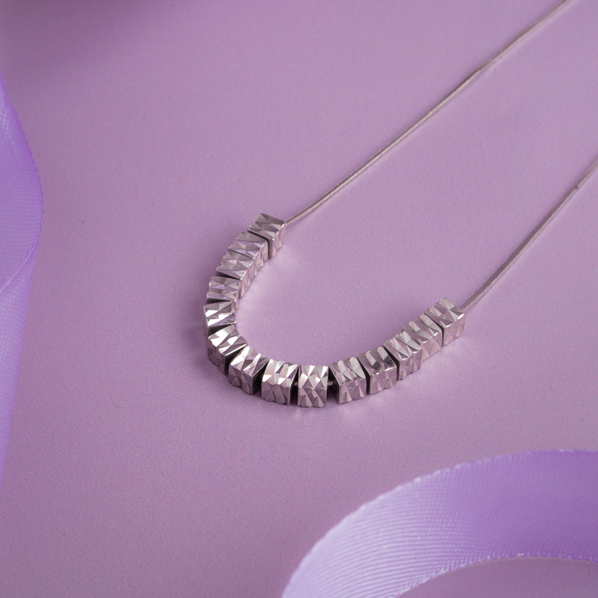 Silver curved necklace with faceted geometric beads